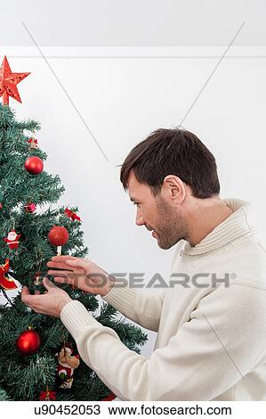 Man decorating the christmas tree View Large Photo Image Stock Image - Man decorating the christmas tree. Fotosearch
