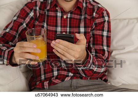 Man drinking a juice and checking his phone View Large Photo Image Stock Image - Man drinking a juice and checking his phone. Fotosearch