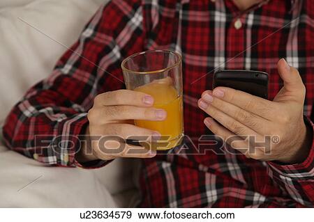 Stock Photo - Man drinking a juice and checking his phone. Fotosearch