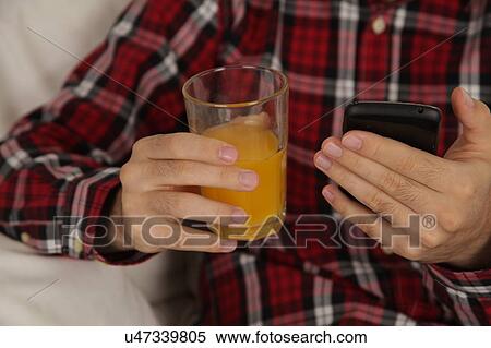 Man drinking a juice and checking his phone View Large Photo Image Stock Photography - Man drinking a juice and checking his phone. Fotosearch