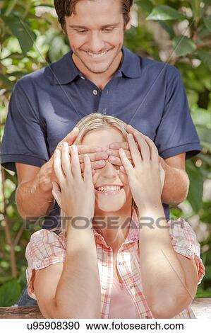 Stock Image - Man giving a surprise to his girlfriend. Fotosearch