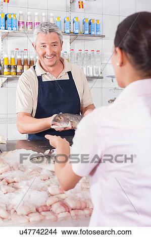 Man giving a white salmon to a costomer View Large Photo Image Picture - Man giving a white salmon to a costomer. Fotosearch
