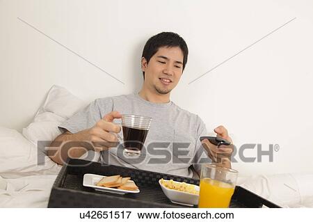 Man having a breakfast and watching tv View Large Photo Image Stock Photo - Man having a breakfast and watching tv. Fotosearch