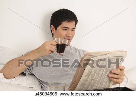 Stock Photograph - Man having a breakfast while reading the newspaper. Fotosearch