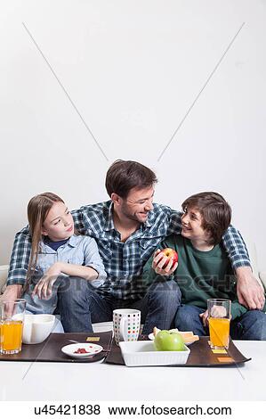 Stock Photo - Man having a breakfast with your two childrens. Fotosearch