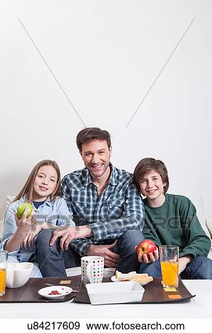 Stock Photo - Man having a breakfast with your two childrens. Fotosearch