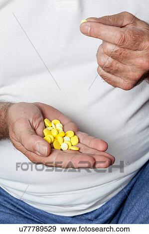 Stock Photo - Man holding a lot of pills. Fotosearch