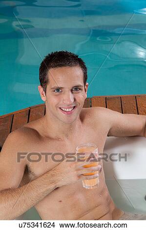 Picture - Man inside a jacuzzi drinking juice. Fotosearch