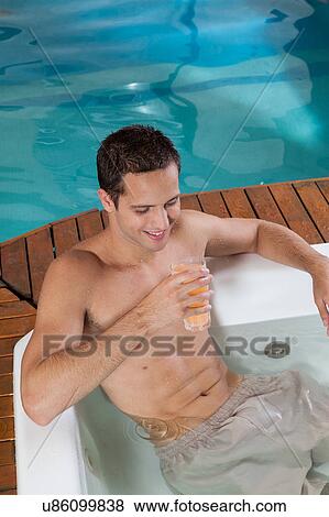 Stock Photo - Man inside a jacuzzi drinking juice. Fotosearch