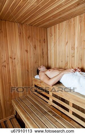 Stock Image - Man laid inside the sauna. Fotosearch