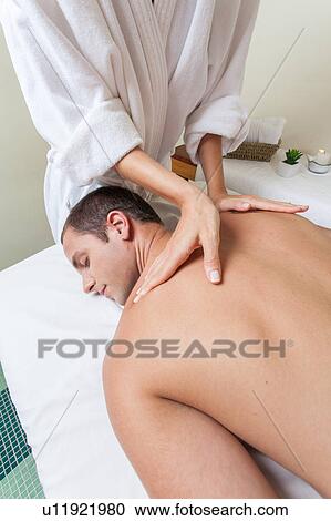 Stock Image - Man laid receiving massage. Fotosearch