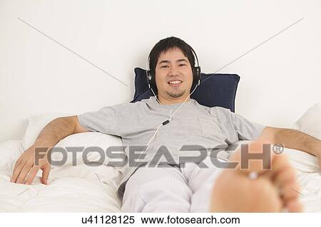 Man listening music lying View Large Photo Image Stock Photography - Man listening music lying. Fotosearch