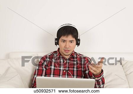 Man listening to music and looking at computer View Large Photo Image Stock Image - Man listening to music and looking at computer. Fotosearch