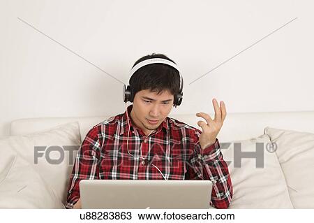 Man listening to music and looking at computer View Large Photo Image Stock Image - Man listening to music and looking at computer. Fotosearch