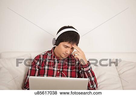 Stock Photo - Man listening to music and looking at computer. Fotosearch