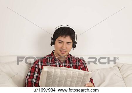 Picture - Man listening to music and reading the newspaper. Fotosearch