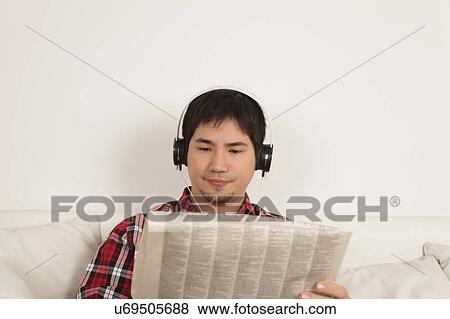 Stock Photo - Man listening to music and reading the newspaper. Fotosearch