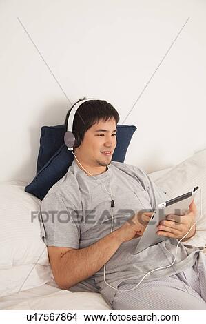 Picture - Man listening to music with the tablet. Fotosearch