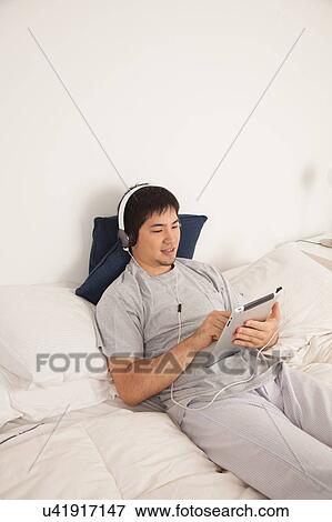 Stock Photo - Man listening to music with the tablet. Fotosearch