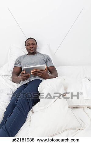 Man looking at camera and holding his tablet View Large Photo Image Stock Photo - Man looking at camera and holding his tablet. Fotosearch