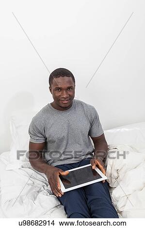 Man looking at camera and touching his tablet View Large Photo Image Picture - Man looking at camera and touching his tablet. Fotosearch