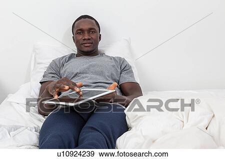 Man looking at camera and touching his tablet View Large Photo Image Stock Photo - Man looking at camera and touching his tablet. Fotosearch