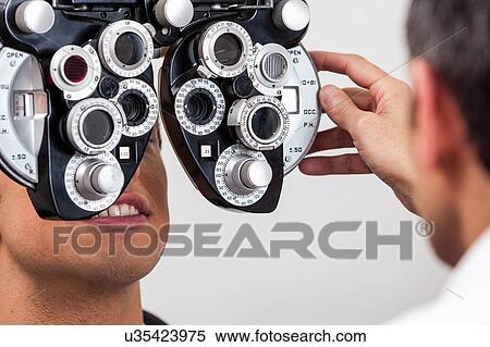 Man looking through the keratometer View Large Photo Image Stock Photography - Man looking through the keratometer. Fotosearch