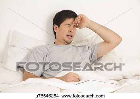 Picture - Man lying with headache. Fotosearch