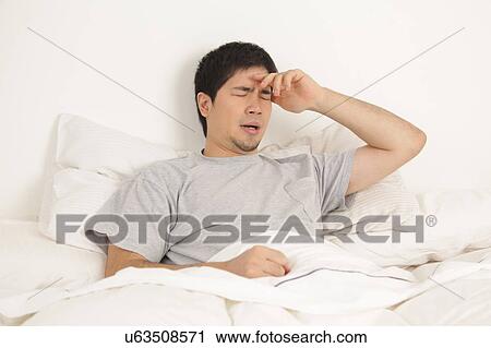 Stock Image - Man lying with headache. Fotosearch