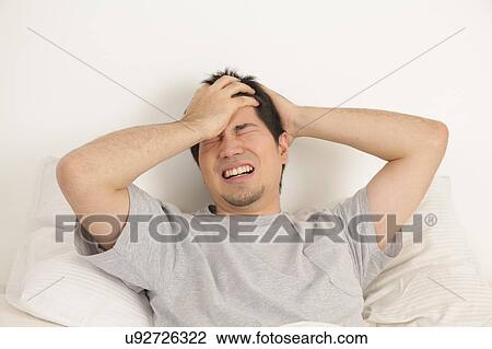 Stock Image - Man lying with headache. Fotosearch