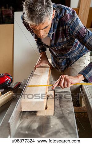 Picture - Man measuring a plank. Fotosearch