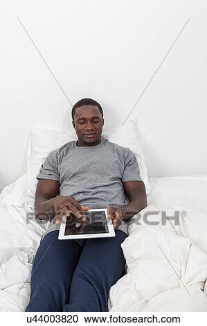 Stock Image - Man playing his tablet. Fotosearch