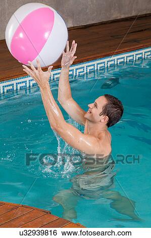 Stock Photograph - Man playing with inflatable ball inside the pool. Fotosearch