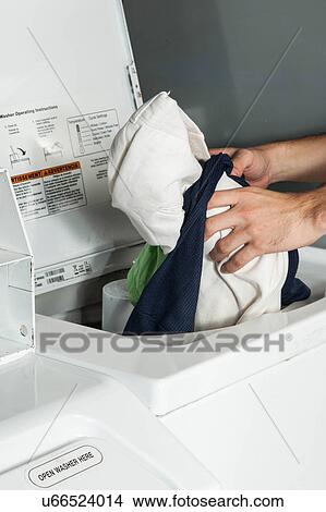 Picture - Man putting clothes in the washing machine. Fotosearch