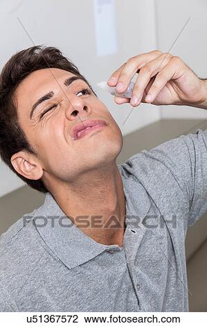 Stock Image - Man putting eye drops. Fotosearch