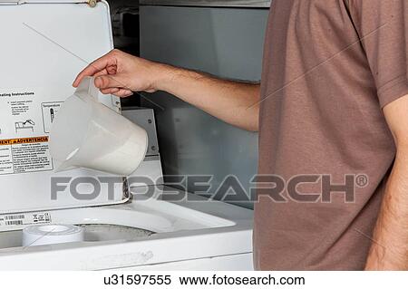 Stock Photography - Man putting soap in the washing machine. Fotosearch