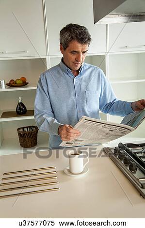 Stock Photography - man reading a newspaper in the kitchen. Fotosearch