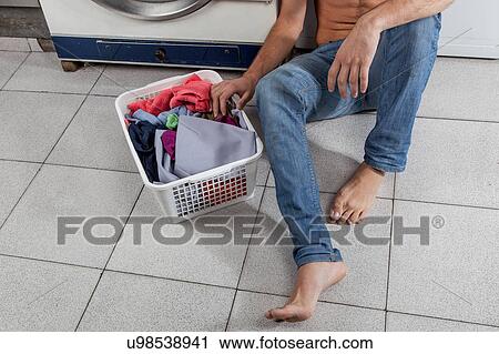 Stock Image - Man sitting on the floor in the laundry. Fotosearch