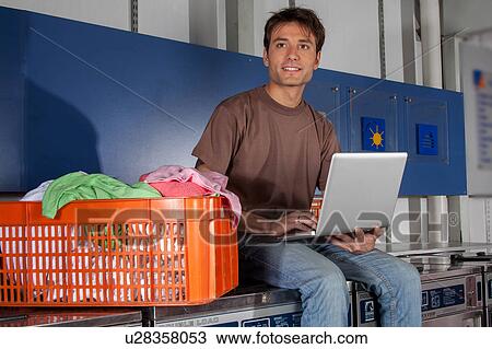 Stock Image - Man sitting on top of the washing machine. Fotosearch