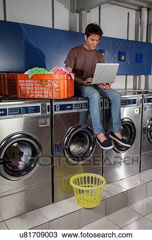 Stock Image - Man sitting on top of the washing machine. Fotosearch
