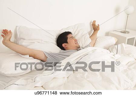 Man stretching in his bed View Large Photo Image Stock Photo - Man stretching in his bed. Fotosearch