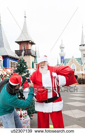 Stock Photo - Man taking a photo to santa claus. Fotosearch