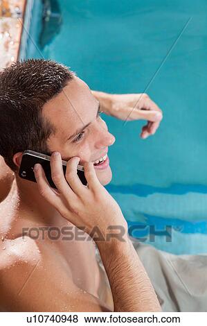 Stock Photo - Man talking on mobile inside the pool. Fotosearch