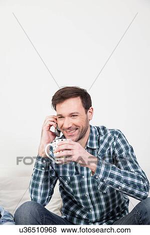 Man talking on the cellphone holding a cup of tea View Large Photo Image Stock Photo - Man talking on the cellphone holding a cup of tea. Fotosearch