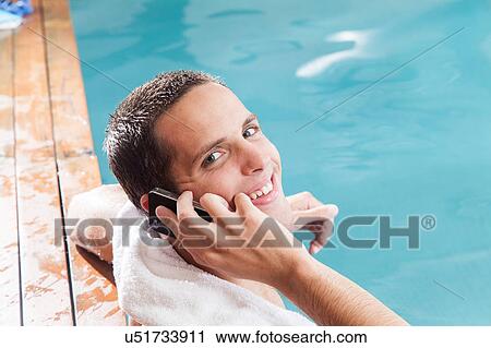 Stock Image - Man talkking on mobile inside the pool. Fotosearch