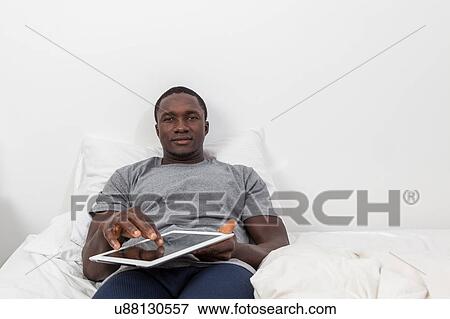 Stock Photo - Man touching the screen of his tablet. Fotosearch