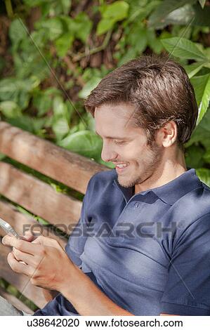 Man using a cellphone in the park View Large Photo Image Stock Image - Man using a cellphone in the park. Fotosearch