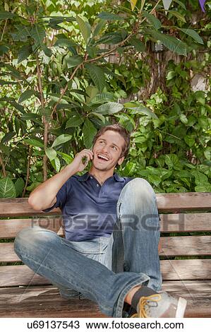 Stock Image - Man using a cellphone in the park. Fotosearch