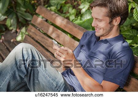 Stock Photography - Man using a cellphone in the park. Fotosearch
