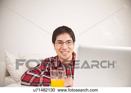 Stock Image - Man using the computer and looking at camera. Fotosearch